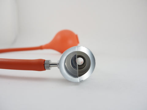 Close up of the Bruenings half lens diagnostic head with a tubing connector and a Bruenings Ear Specula. Used by Otolarygologists in surgical procedures and in office for diagnosis
